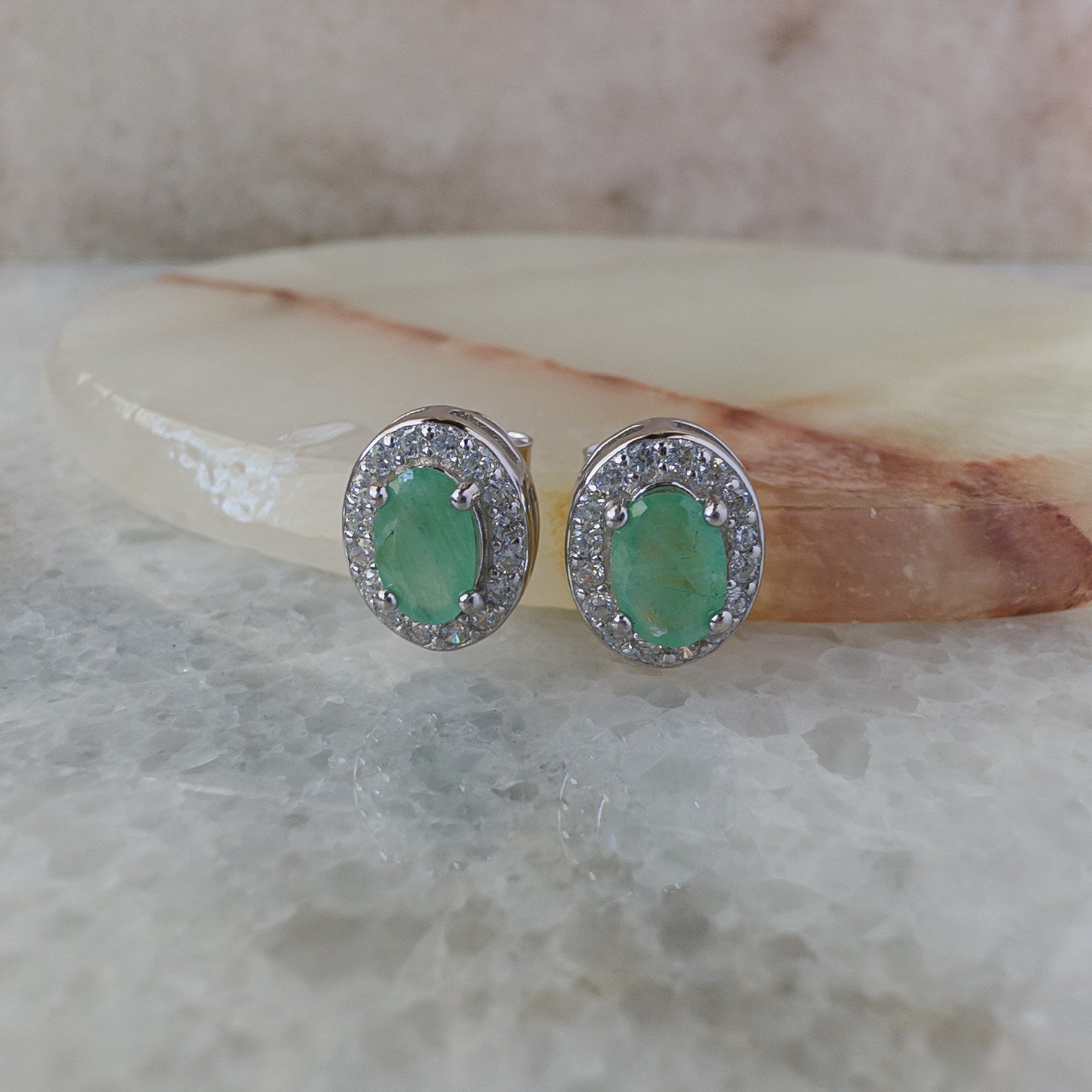 Aretes de plata con esmeralda natural oval y halo de circonias